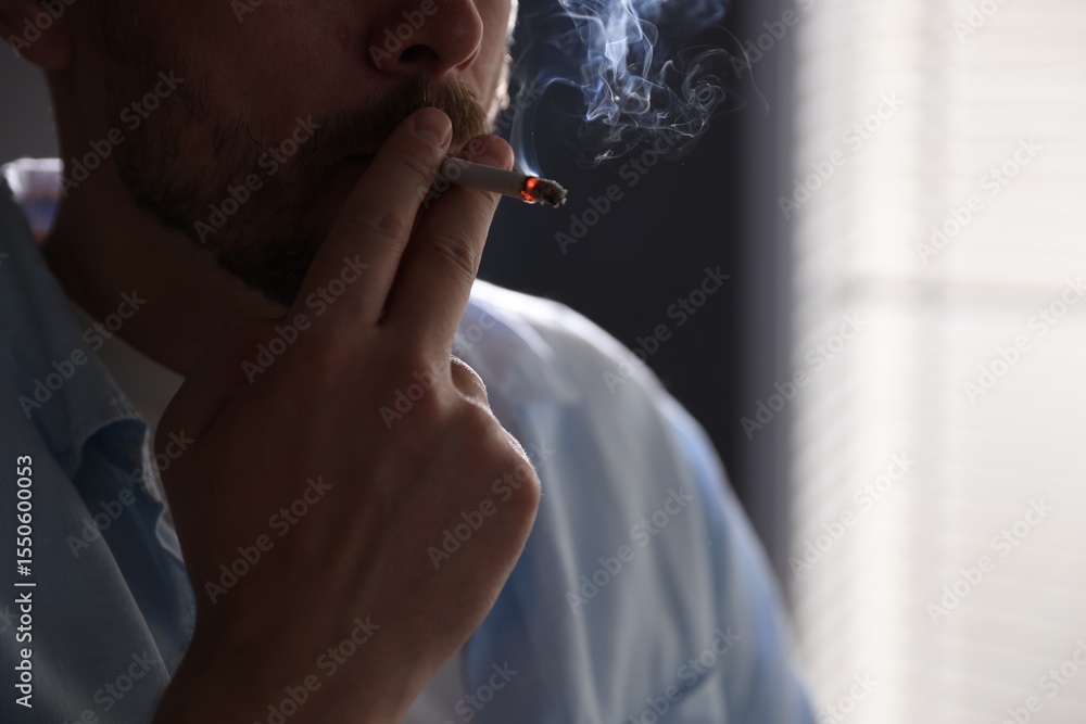 Fototapeta premium Man smoking cigarette on blurred background, closeup