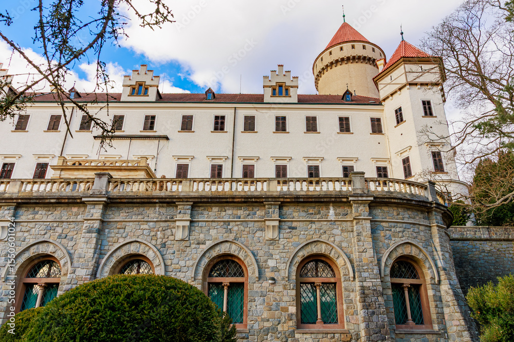Fototapeta premium Historic european castle with stone facade and red turrets under blue sky