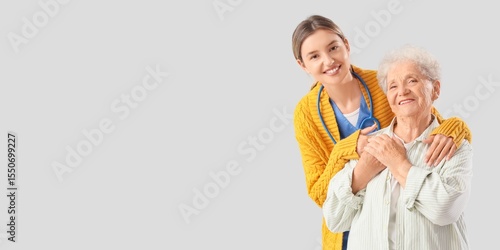 Nurse hugging senior woman on light background with space for text
