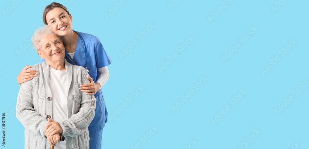 © Pixel-Shot - Nurse hugging senior woman on blue background with space for text