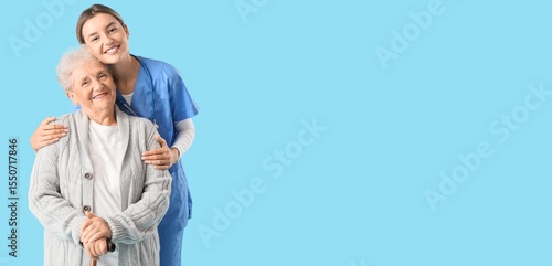 Nurse hugging senior woman on blue background with space for text