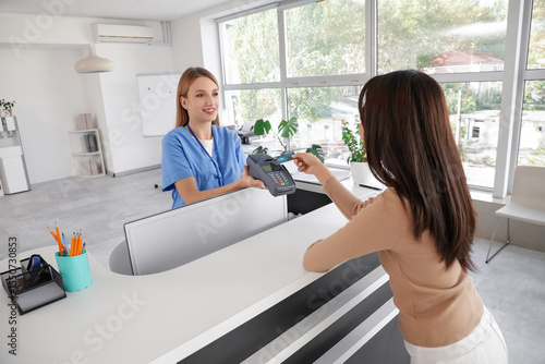 Female medical intern receiving payment from patient at reception in clinic