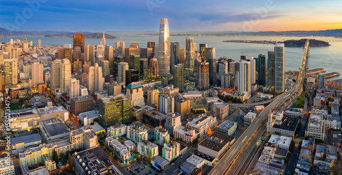 Aerial view of the San Francisco skyline at dusk in California, USA. The photo shows the city's skyscrapers and the Bay Bridge, highlighting urban development.