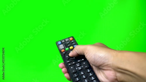 Hand holds TV remote and press the button, green screen background