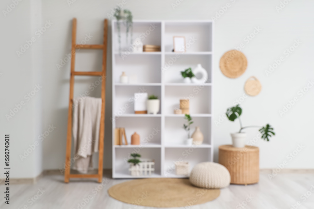 Fototapeta premium Blurred view of light room with shelf unit, ladder and plants