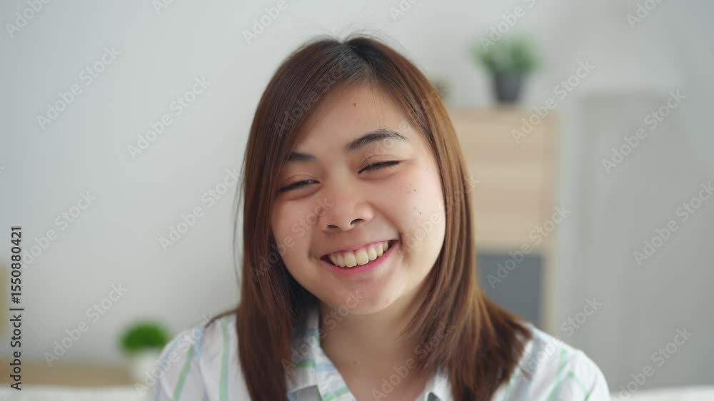 Portrait of a young woman with straight hair wearing a striped shirt sitting in a sunny room with a light and relaxed atmosphere Portrait of a young woman with straight hair wearing a striped shirt sitting in a sunny room with a light and relaxed atmosphere