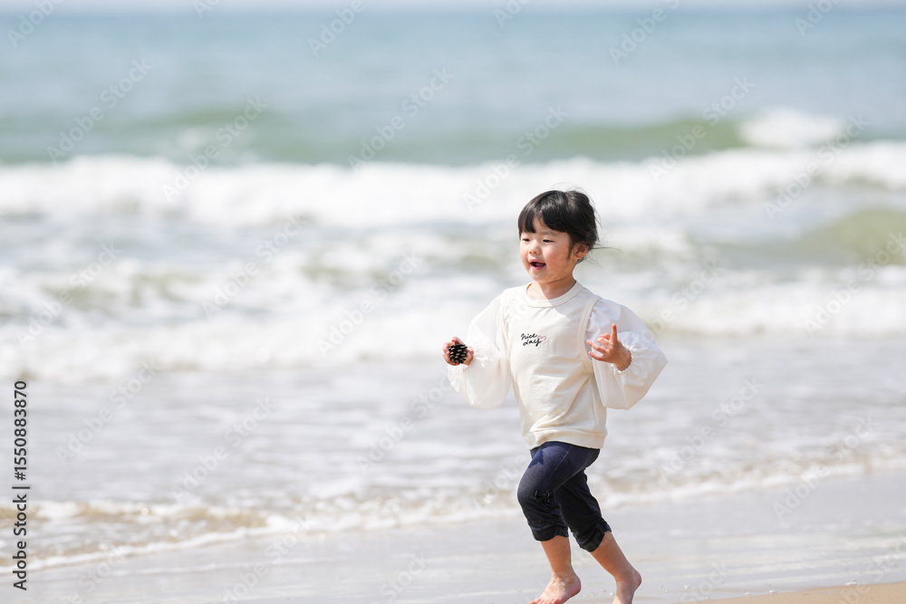 In early March, a 3-year-old Japanese girl in a white outfit runs and plays alone on a sandy beach with a view of the Sea of Japan. A cheerful spring moment filled with innocence and freedom. In early March, a 3-year-old Japanese girl in a white outfit runs and plays alone on a sandy beach with a view of the Sea of Japan. A cheerful spring moment filled with innocence and freedom.