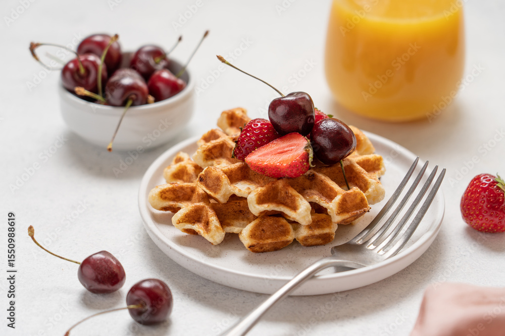 Close up view of waffles with berries topping and orange juice. Nutritious breakfast on white background Close up view of waffles with berries topping and orange juice. Nutritious breakfast on white background