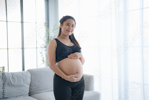 Pregnant asian woman holds hands on belly touching her baby caring about her health Beautiful happy pregnant woman tender mood photo of pregnancy. Free Download Pregnant asian woman holds hands on belly touching her baby caring about her health Beautiful happy pregnant woman tender mood photo of pregnancy. - GFXLoad