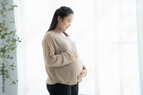 Pregnant asian woman holds hands on belly touching her baby caring about her health Beautiful happy pregnant woman tender mood photo of pregnancy. Free Download Pregnant asian woman holds hands on belly touching her baby caring about her health Beautiful happy pregnant woman tender mood photo of pregnancy. - GFXLoad