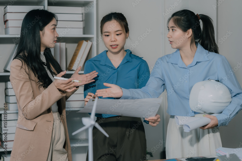 Fototapeta premium business women talking on cell phone Three young Asian female real estate agents meet to discuss selling a house in the office.