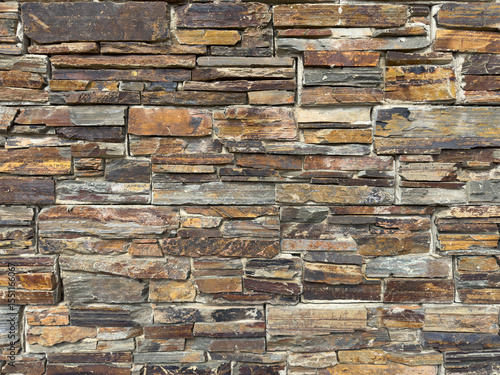 Rustic Charm: Textured Stone Wall with Earthy Hues and Staggered Stonework