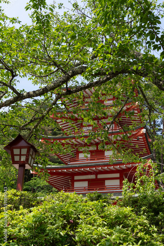 Green trees encircle a striking red Japanese temple Green trees encircle a striking red Japanese temple