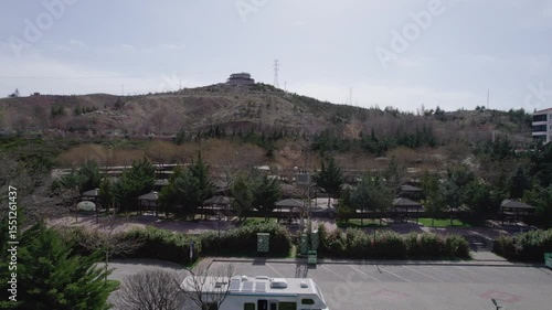A big white motorhome is driving along the highway filming from a drone