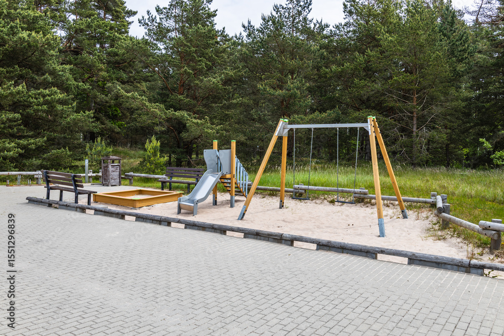 Fototapeta premium Empty Forest Playground with Wooden Swing Set, Metal Slide and Sandbox on Paved Park Surface