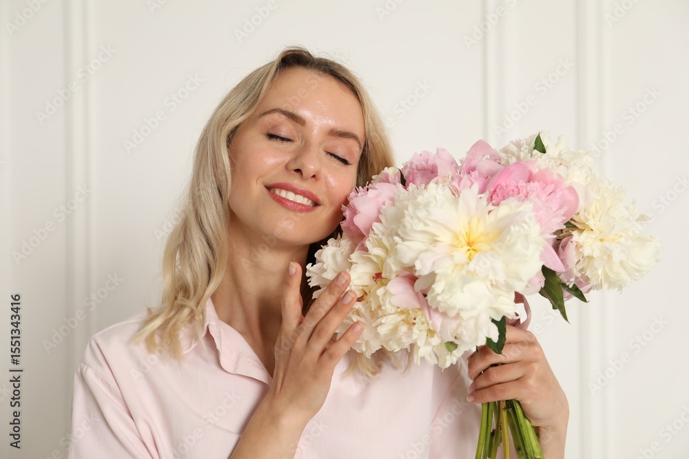 Happy woman with bouquet of beautiful peonies near white wall indoors Happy woman with bouquet of beautiful peonies near white wall indoors