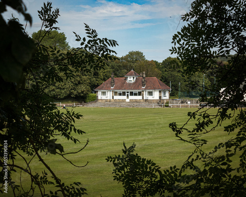  A view across a cricket pitch to the elegant red- roofed dressing rooms and pavilion in Saltaire