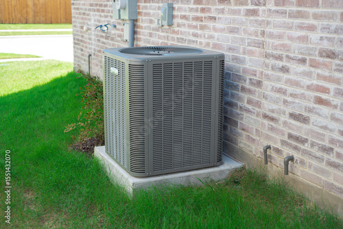 Cuadro en lienzo Small landscaping shrub, grassy yard and central air conditioning condenser unit