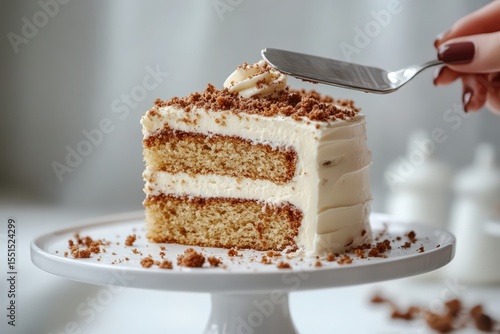  Woman lifting cake slice on white, frosting smooth, moist layers visible, crumbs scattered casually, inviting dessert setup.