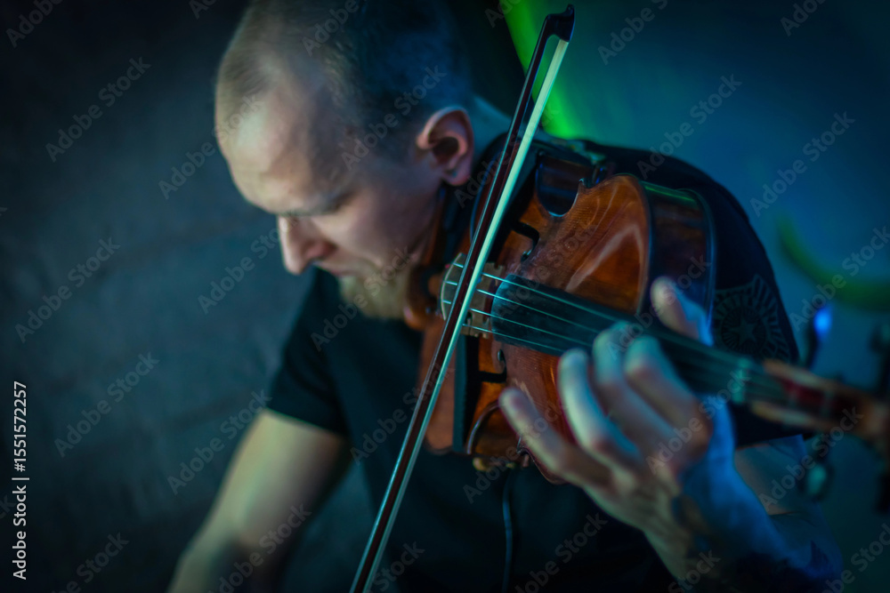 Fototapeta premium The violinist plays the violin. Brutal man with a beard playing the violin fatal simony. Close-up