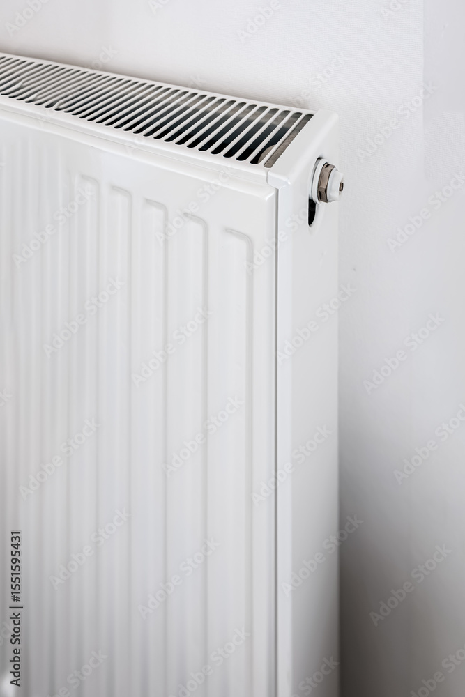 White panel radiator with top ventilation slots and metal valve, photographed from side angle in bright minimalist interior, concept of efficient home heating White panel radiator with top ventilation slots and metal valve, photographed from side angle in bright minimalist interior, concept of efficient home heating
