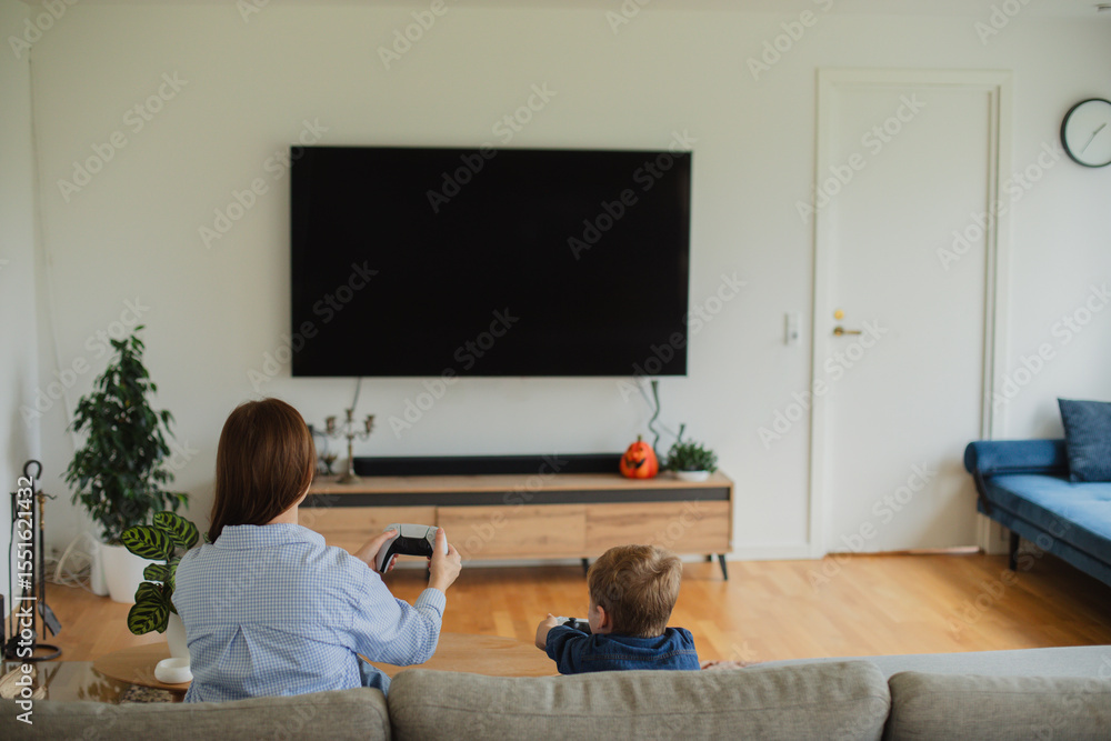 custom made wallpaper toronto digitalA cheerful mother and her young son sitting on a cozy couch, fully immersed in playing video games together.