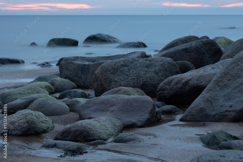 Obraz premium Serene Coastal View with Rocks and Calm Seascape at Sunset