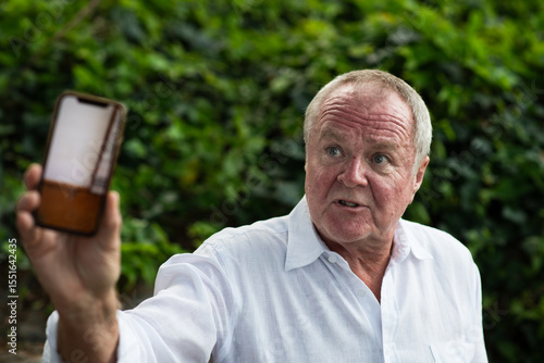frustrated senior man showing his phone screen as he tells a story