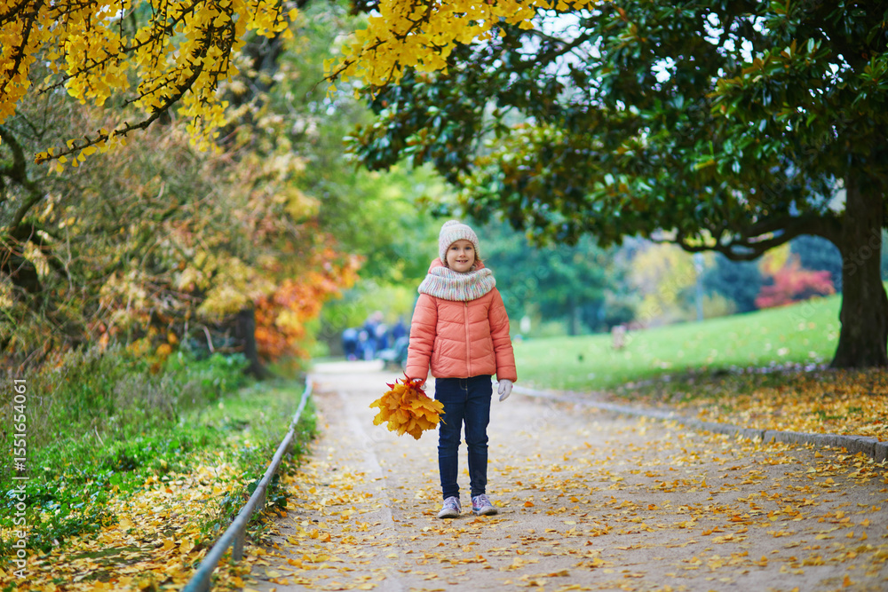 Obraz premium Cheerful little girl enjoying her walk in autumn park in Paris, France.