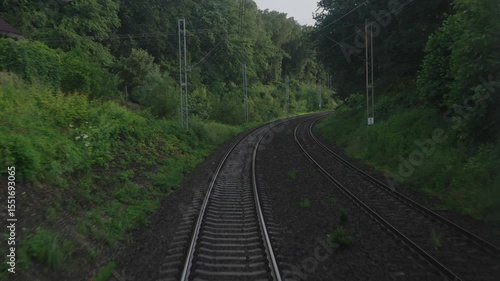 View of the railway tracks through the train window from the last carriage. European train travel, Czech Republic. Railway and countryside in the forest during train movement.