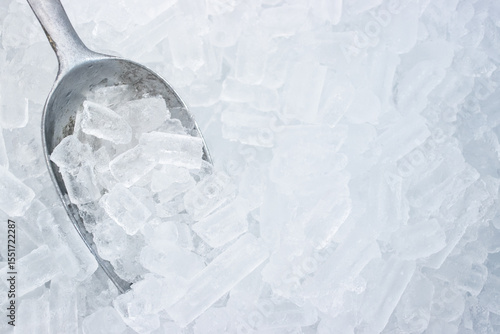 Cylindrical ice cubes with a metal scoop in an ice bin, commonly used for chilling beverages or food in restaurants.
