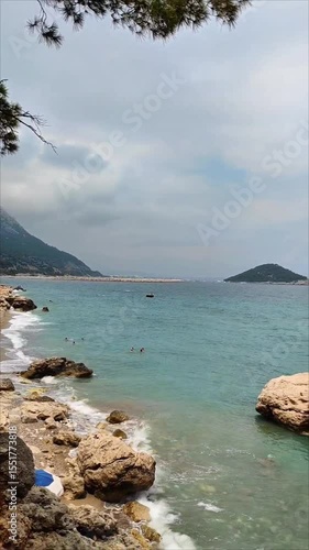 Panorama of the gulf of the Mediterranean Sea with blue water with waves, with a shore with green vegetation, in summer