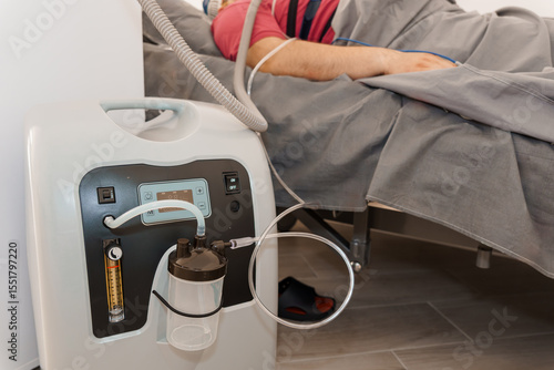 Patient Receiving Oxygen Therapy with Concentrator Machine in Modern Hospital Bed. White and Red Equipment, Clinical Setting, Healthcare Concept
