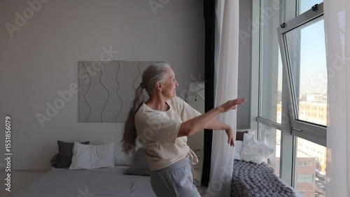 senior woman  listens to music and dances at home in the morning. seniors llifestyle. International Music Day. dopamine hobbies