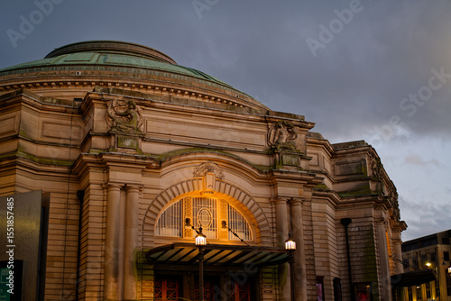 Illuminated Usher Hall in Edinburgh at dusk with clouds. Facade of historic building in the city center with beautiful architecture. Front of concert hall with lights and dark clouds in the background