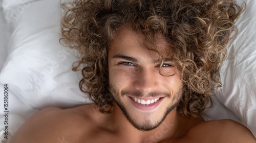 A man lies in bed, beaming with joy, surrounded by the comfort of soft white sheets on a serene morning