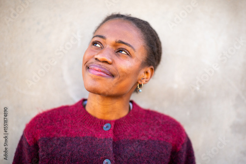 Thoughtful African young woman smiling and looking up