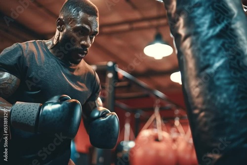 Wallpaper Mural a man wearing boxing gloves punching a punching bag in a boxing gym Torontodigital.ca