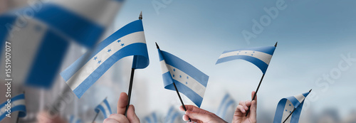 Honduras flags in their hands on a blurred urban background