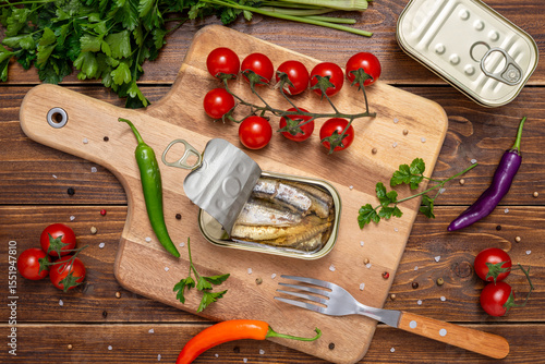 An open can of sardines on cutting wooden board
