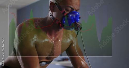 Cycling adult male leaning over bike handlebars in clinical lab, with mask tubing electrodes graph