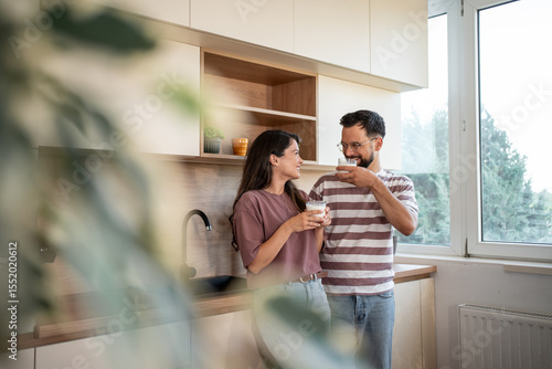 Happy couple drinking milk in modern kitchen, enjoying morning routine together