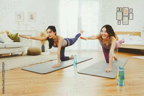 Wallpaper Mural Two asian female friends take care of their health by playing indoor sports at home practicing yoga on a yoga mat holding their arms in unison : Healthy indoor sports concept. Torontodigital.ca