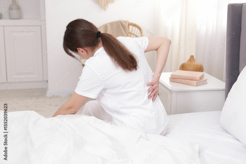 Woman suffering from back pain on bed at home Woman suffering from back pain on bed at home