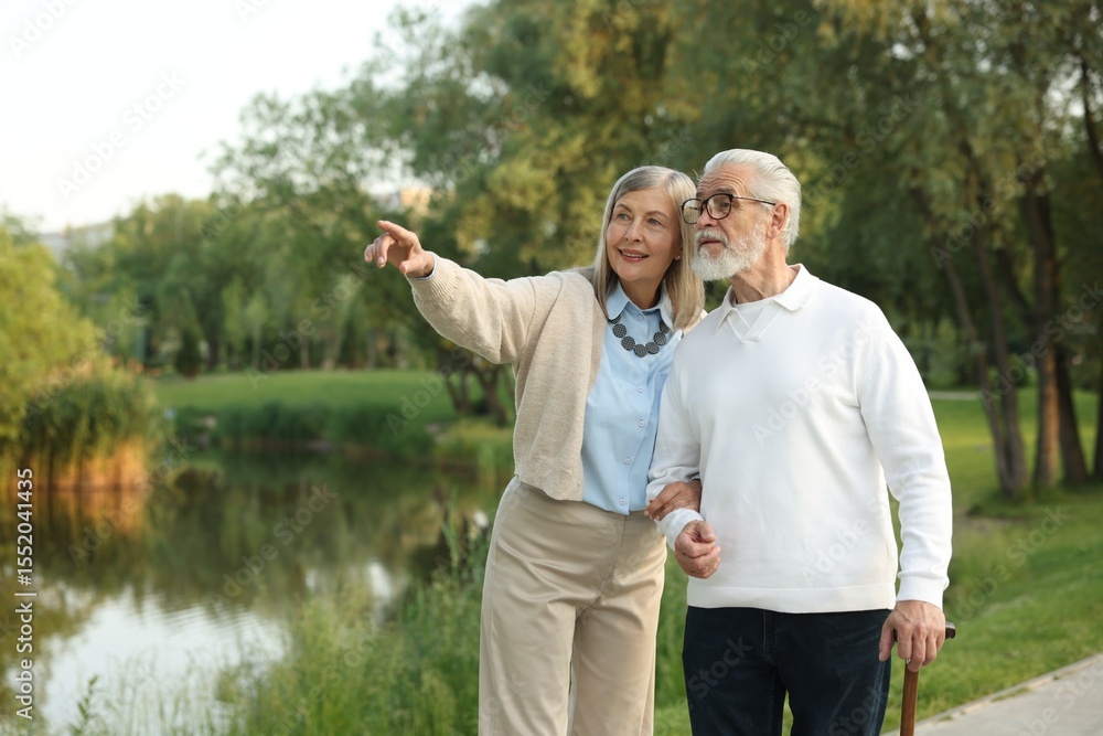 Lovely senior couple walking together near lake in park Lovely senior couple walking together near lake in park