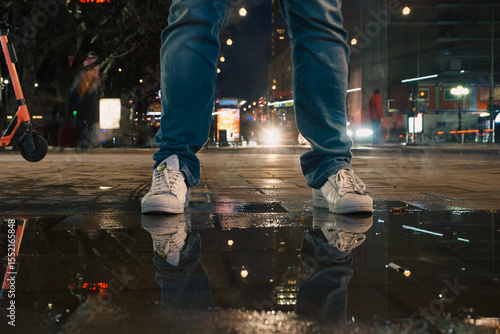 Fotografie A man standing at a puddle during night