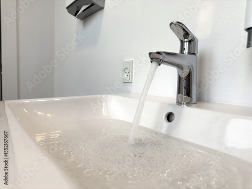 Water flowing from the faucet in the bathroom. Clogged sink