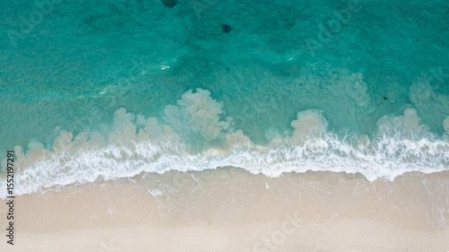 Top down view of ocean waves gently washing over sandy beach shoreline, seamless looping 4k time-lapse animation video background. Nature concept