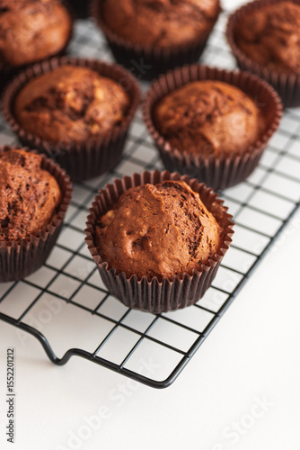 Fototapeta Naklejka Na Ścianę i Meble -  Freshly baked chocolate muffins on a cooling rack. Soft focus