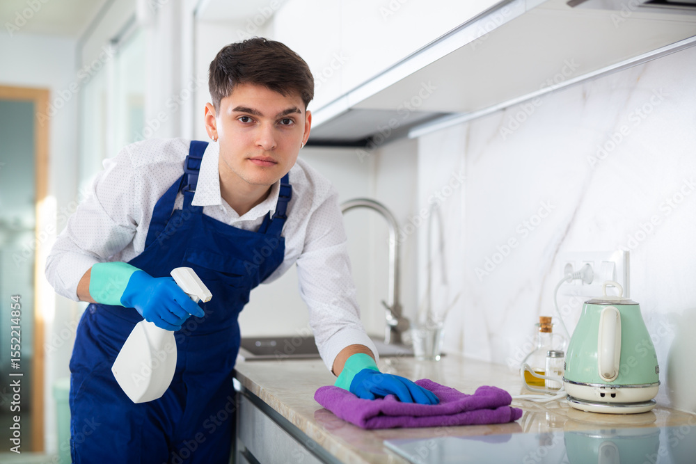 Obraz premium Male professional cleaner cleaning the kitchen countertop